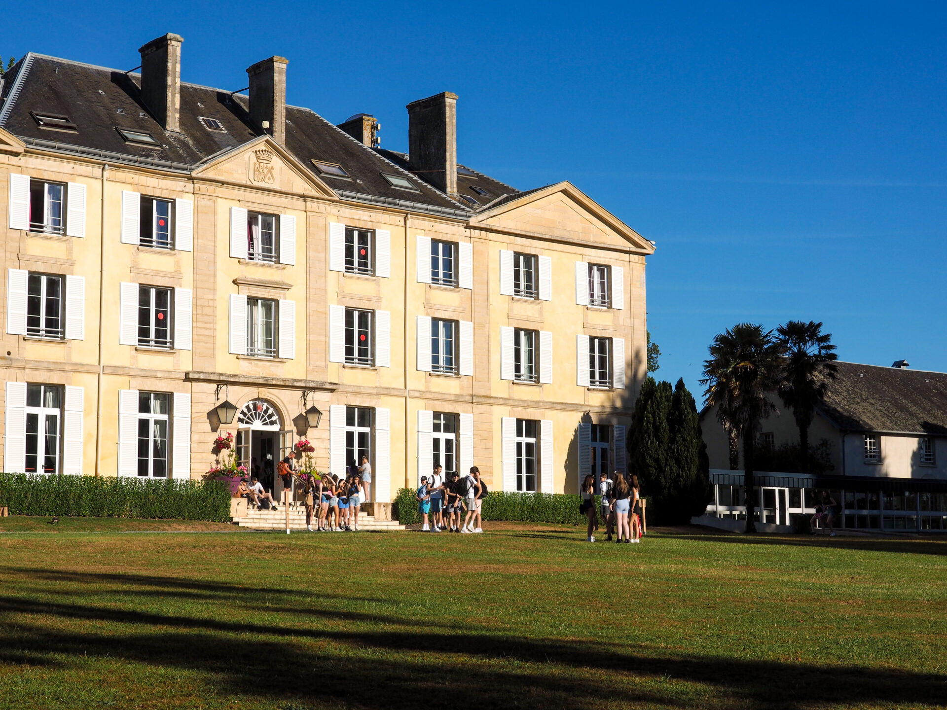 Group of students coming out of the Chateau du Molay on a sunny day