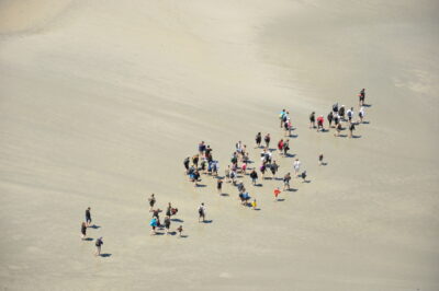 Aerial view of a group walking on the sand to the Mont Saint Michel