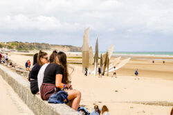 Students sitting on Omaha Beach next to famous war memorial