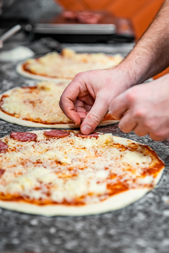 Hands preparing a pizza at a pizza-making class