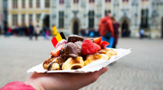 Belgium,Waffle,With,Chocolate,Sauce,And,Strawberries,,Bruges,City,Background,