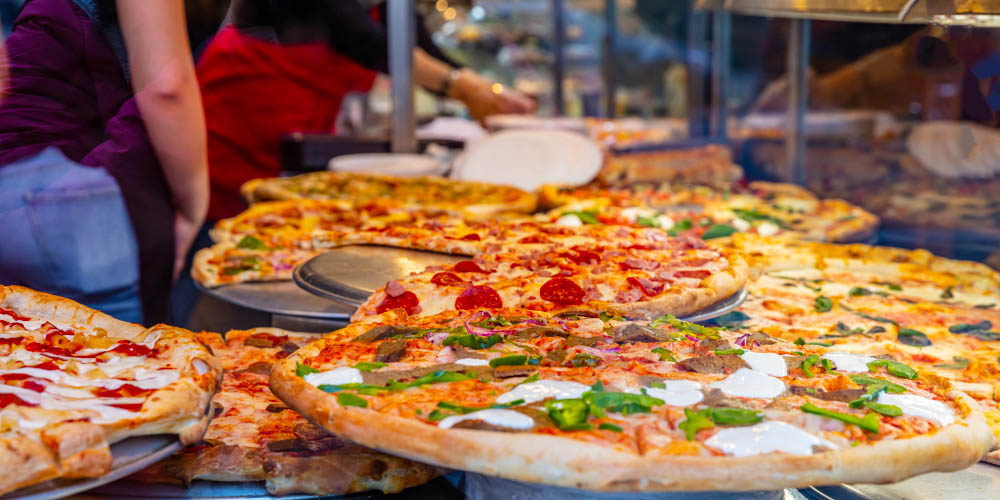 Variety of New York-style pizzas in a shop window display