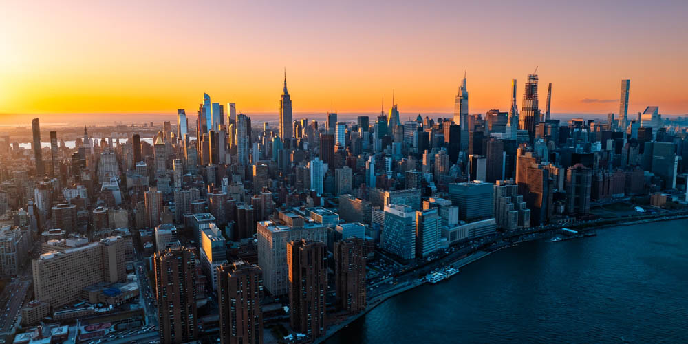 Orange light of setting sun illuminating the skyscrapers and high-rise buildings in New York scenery