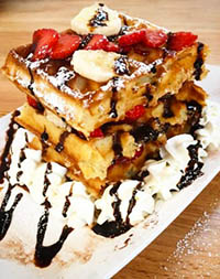 A three-tier waffle with strawberries, bananas, chocolate and Chantilly made at a waffle workshop