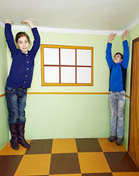 Boy and girl pose in room with optical illusion.