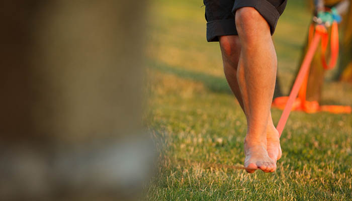 A barefoot person walking on a slackline, slacklining in the daytime, the concept of balance