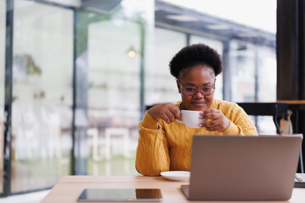 Female teacher drinking coffee while researching her trip online