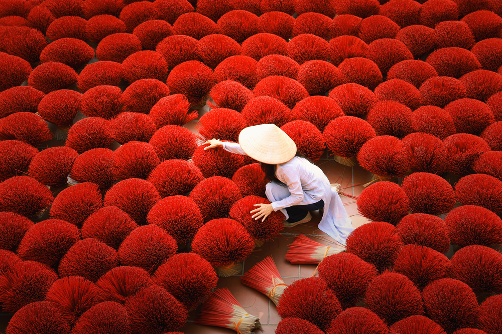 Vietnamese lady drying bright red incense