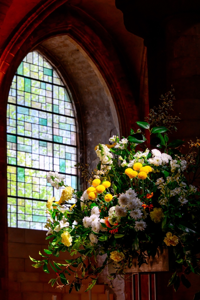 Flower bouquet next to a stained-glass window in a cathedral