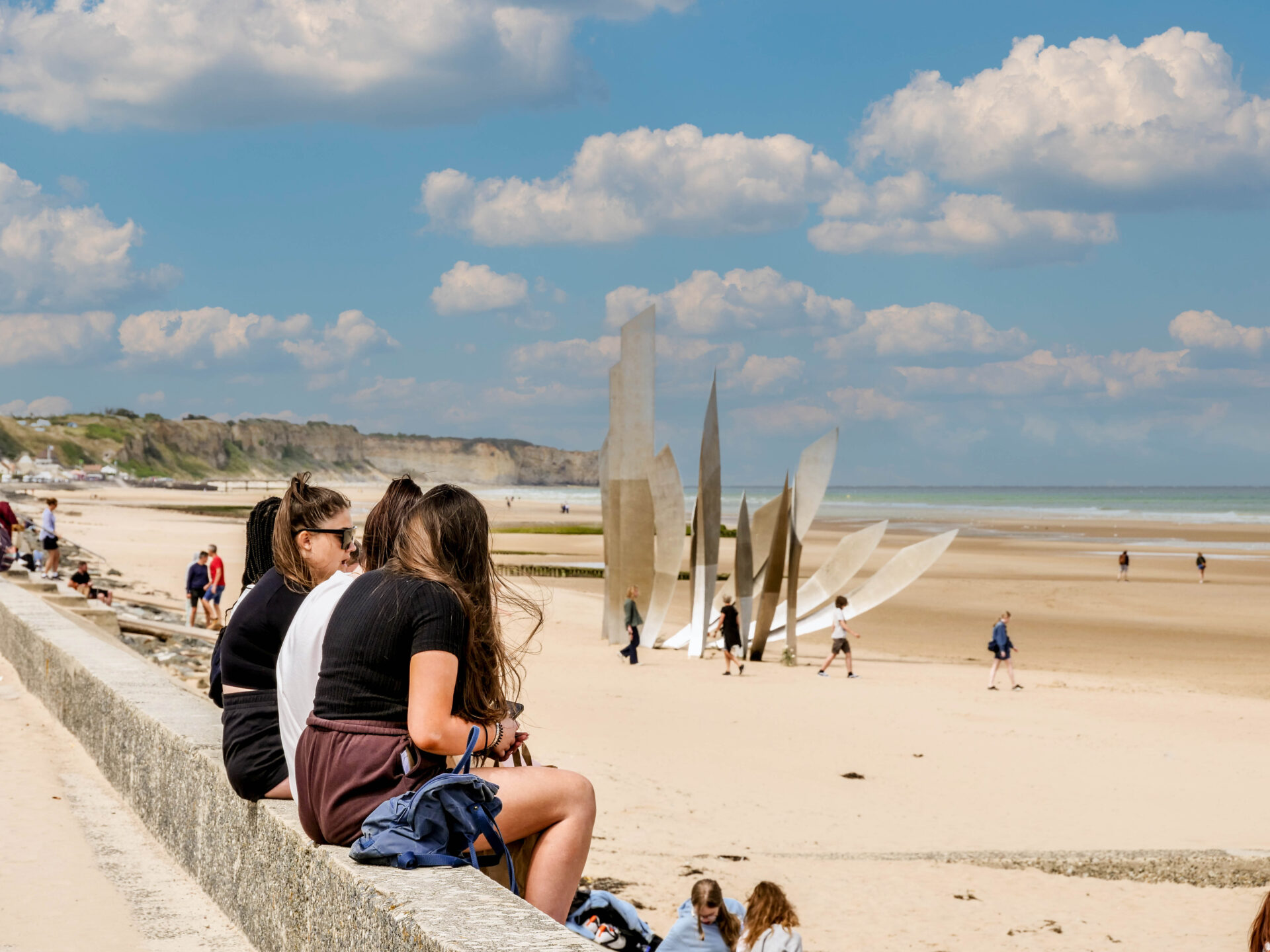 Students sitting on Omaha Beach looking at the memorial