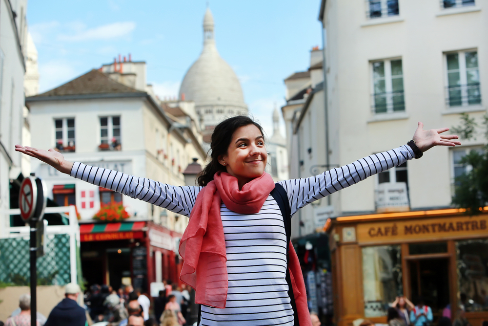 Happy student girl, arms in the air in Montmartre, Paris