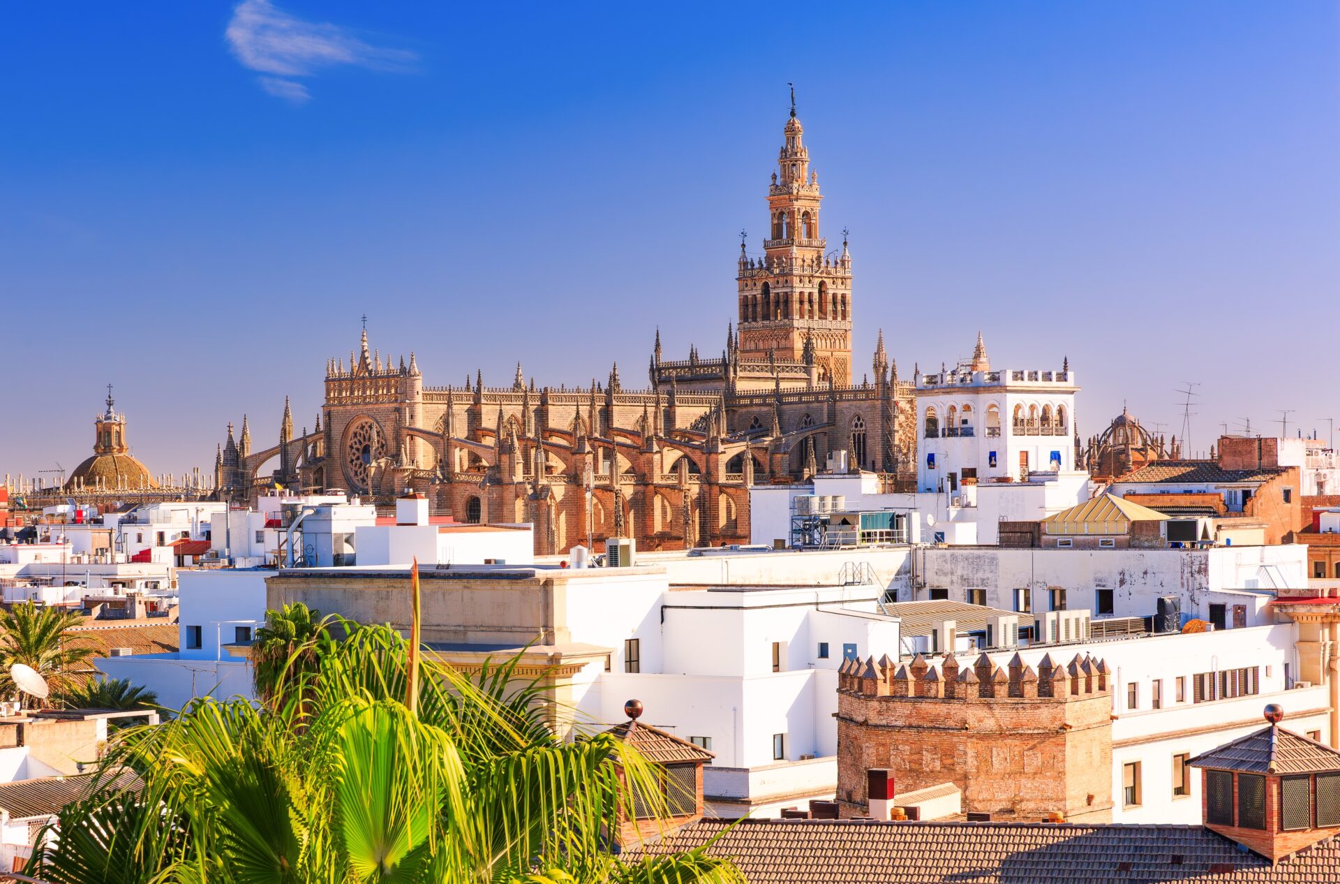 A skyline of Seville, there is lots of blue sky and beige buildings.