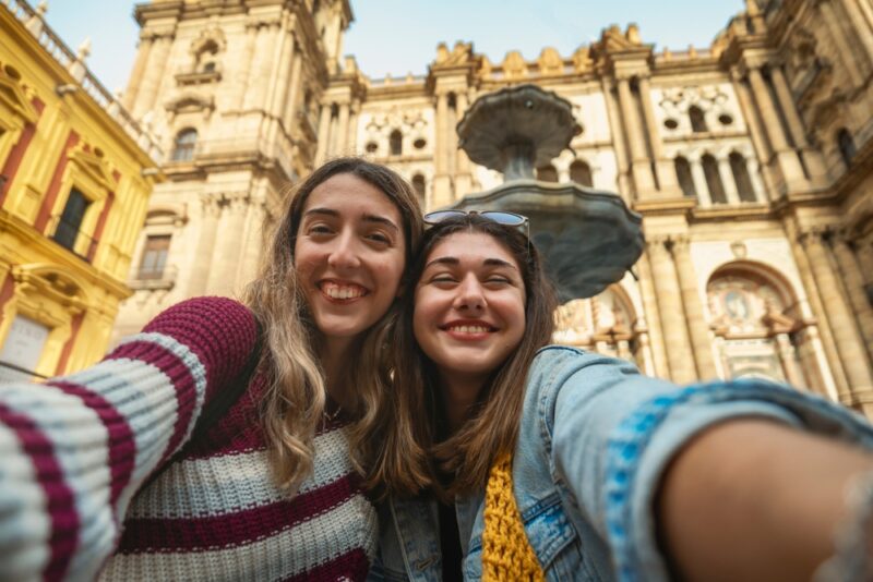 Two female students taking a selfie outside Malaga cathedral in Spain