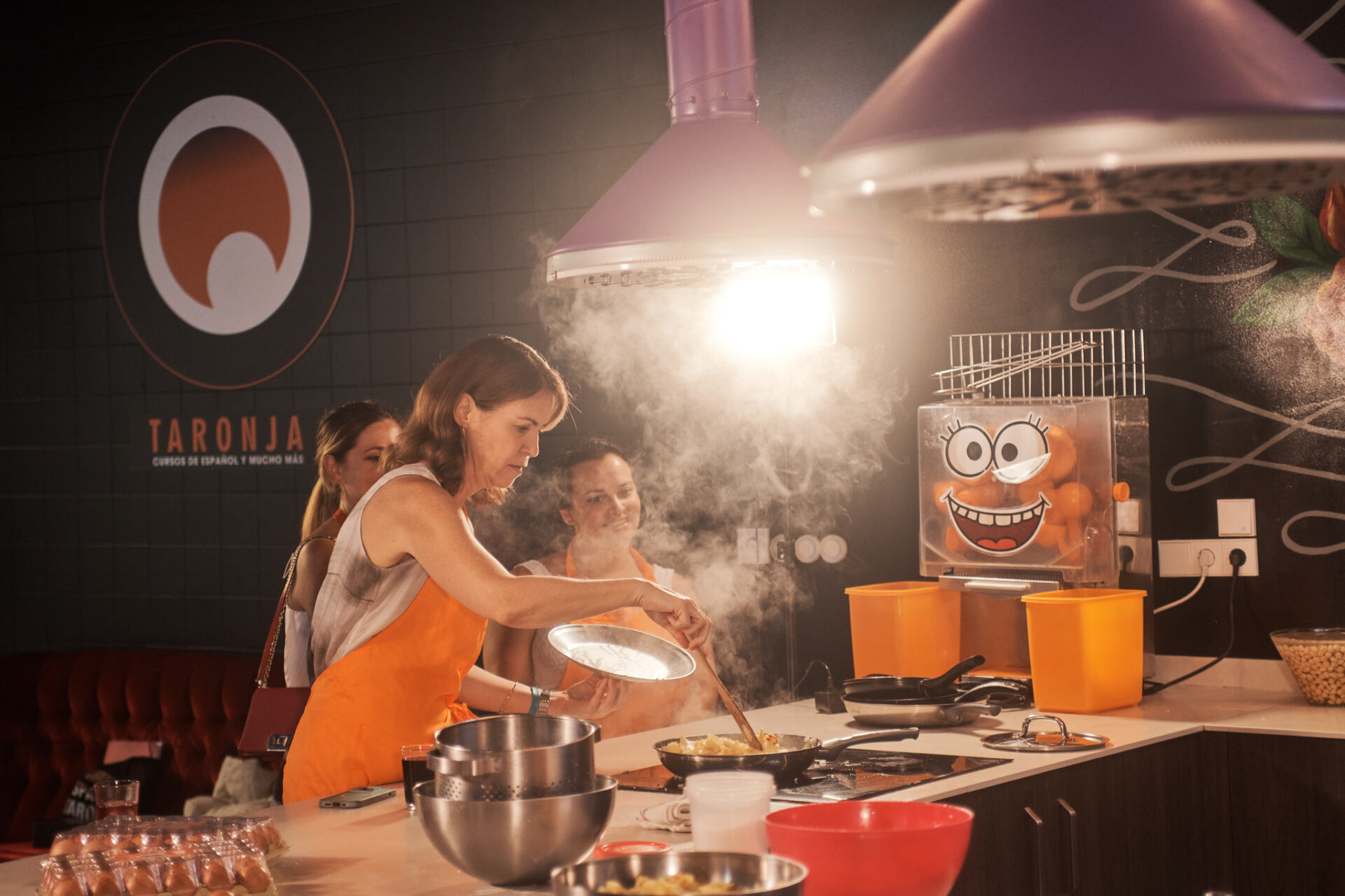 Students wearing orange aprons at a cooking with Taronja School in Valencia